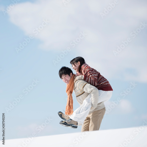 雪原でおんぶをするカップル