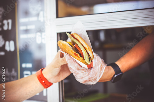 street sale and people concept - happy seller giving burger to customer at food truck