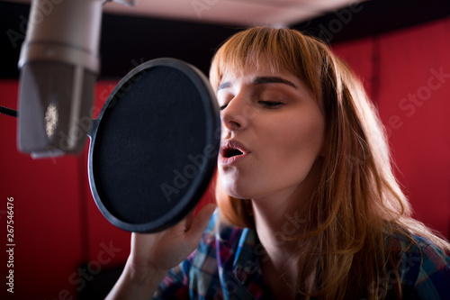 Female with microphone recording a voice for dubbing in music studio