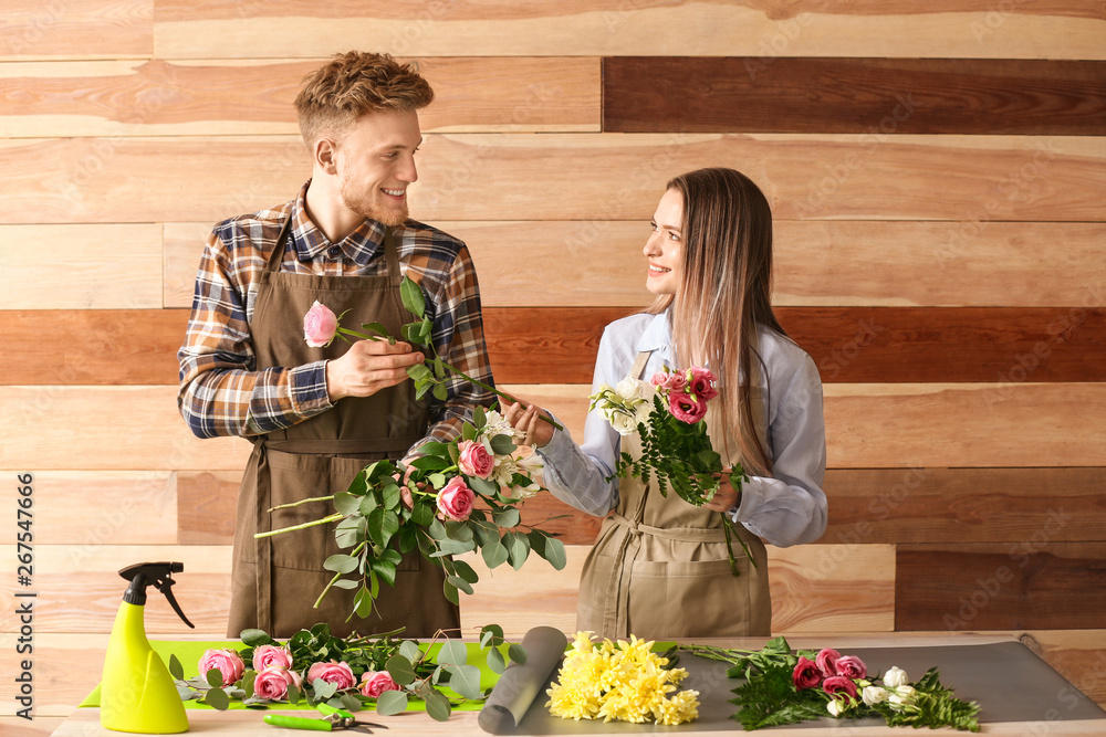 Florists making bouquet at table against wooden background Stock Photo