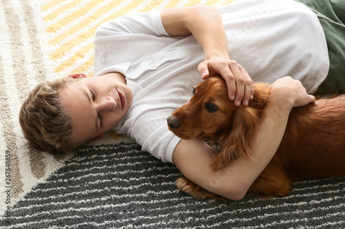 Teenage boy with cute dog lying on carpet at home