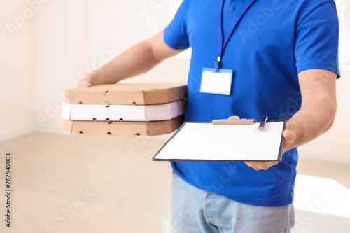 Delivery man with pizza boxes and clipboard indoors