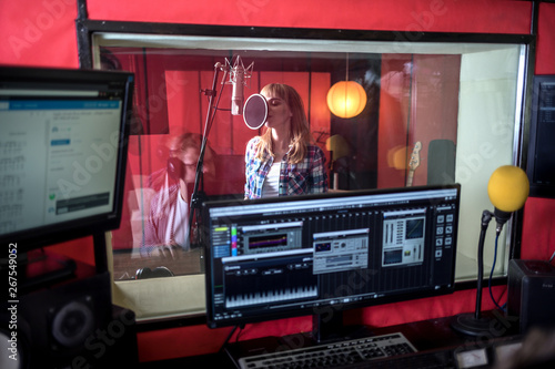 Vászonkép Female singer during vocal recording at music studio