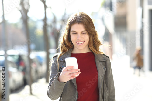 Happy teenage girl walks using smart phone