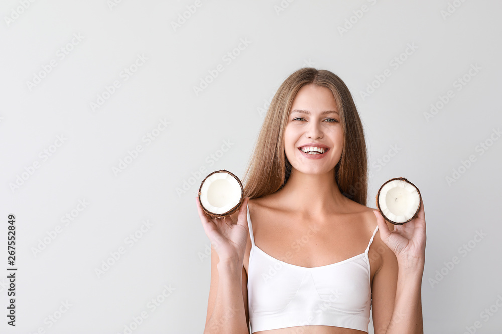 Beautiful young woman with coconut on light background Beautiful young woman with coconut on light background