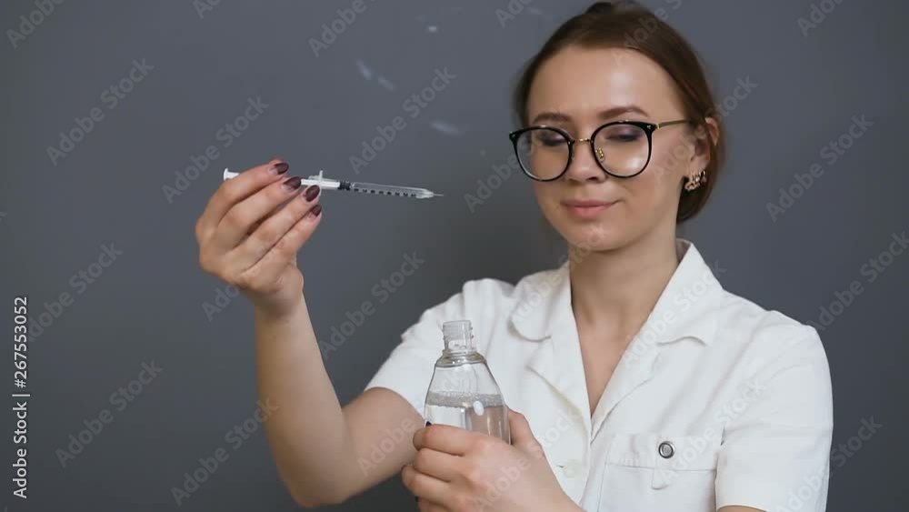 Young female cosmetologist recovering fluid from the ampoule in the clinic. Young female cosmetologist recovering fluid from the ampoule in the clinic.