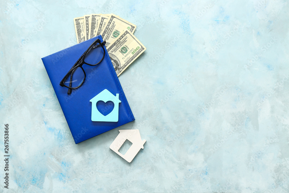 Notebook, figures of houses, glasses and money on table