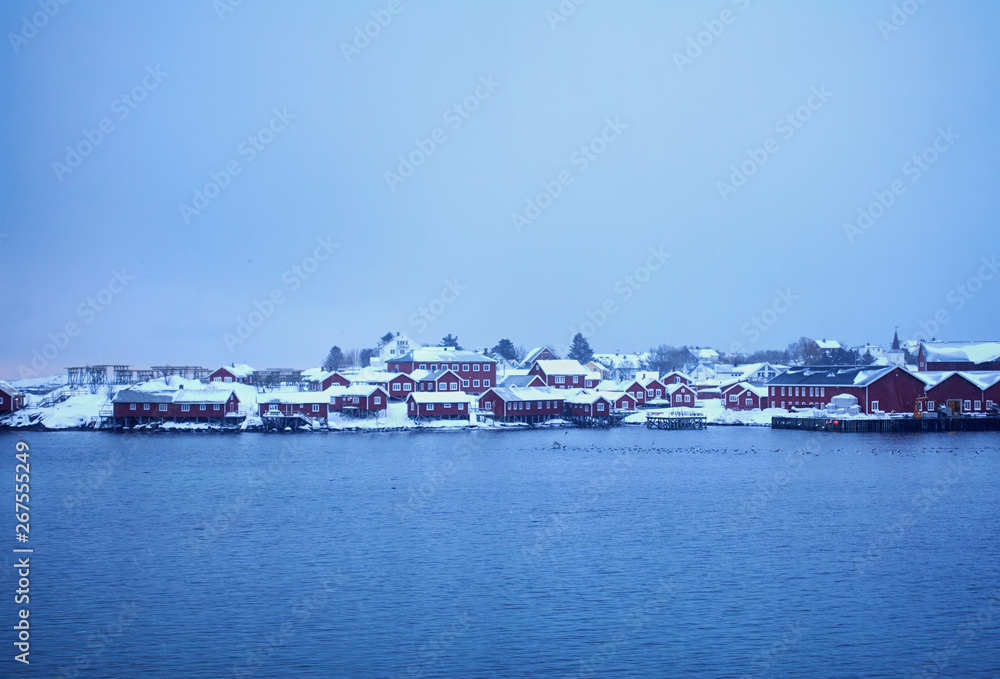 red wooden houses on the shore of a snow-covered lake