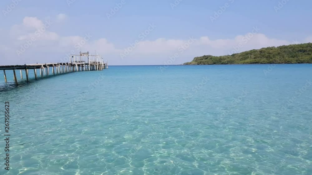 4K. crystal clear blue ocean in summer season with a wooden bridge stretches out into the sea 4K. crystal clear blue ocean in summer season with a wooden bridge stretches out into the sea