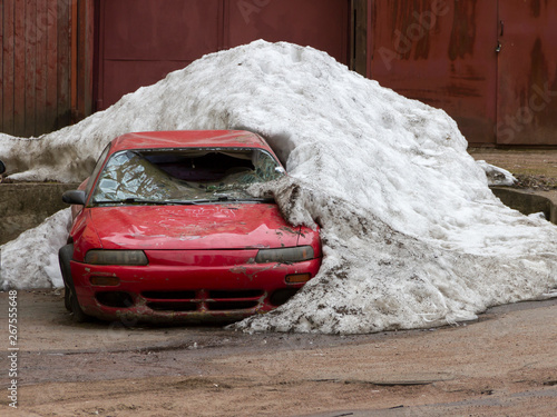 the old half-ruined car in the yard under not thawed snow