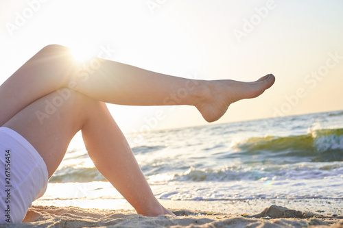 Beautiful woman's legs on sea background. Nice summer day