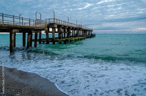 old reinforced concrete pier Batumi at night against the sea