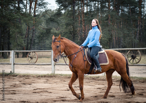 woman riding red don mare horse in spring landscape