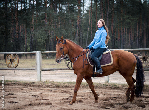 young woman riding red don mare horse in spring landscape