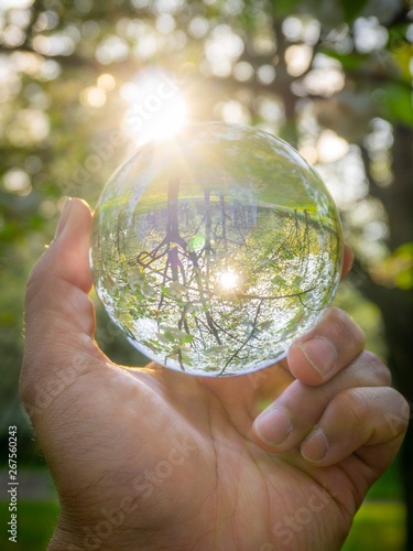 A hand holding a crystal ball for optical illusion. Known as an orbuculum, is a crystal or glass ball and common fortune telling object. Performance of clairvoyance and scrying