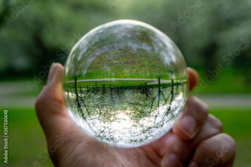 A hand holding a crystal ball for optical illusion. Known as an orbuculum, is a crystal or glass ball and common fortune telling object. Performance of clairvoyance and scrying