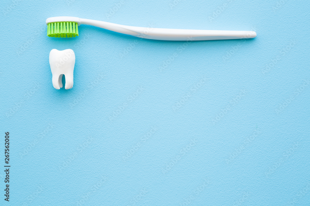 White tooth and toothbrush with green bristles on pastel blue background. People teeth hygiene. Empty place for text, quote, sayings or logo. Closeup. White tooth and toothbrush with green bristles on pastel blue background. People teeth hygiene. Empty place for text, quote, sayings or logo. Closeup.