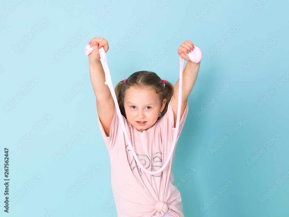 beautiful 8 year old girl is playing with pink slime in front of blue background beautiful 8 year old girl is playing with pink slime in front of blue background