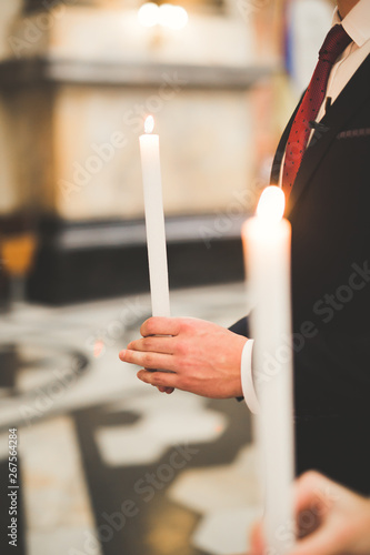 Bride and groom holding candles in church