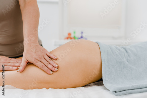 Woman with naked body covered by towel receiving feet massage