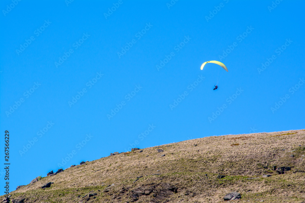 An adventurer glides through the sky over the Yorkshire Moorlands on a clear sunny day An adventurer glides through the sky over the Yorkshire Moorlands on a clear sunny day