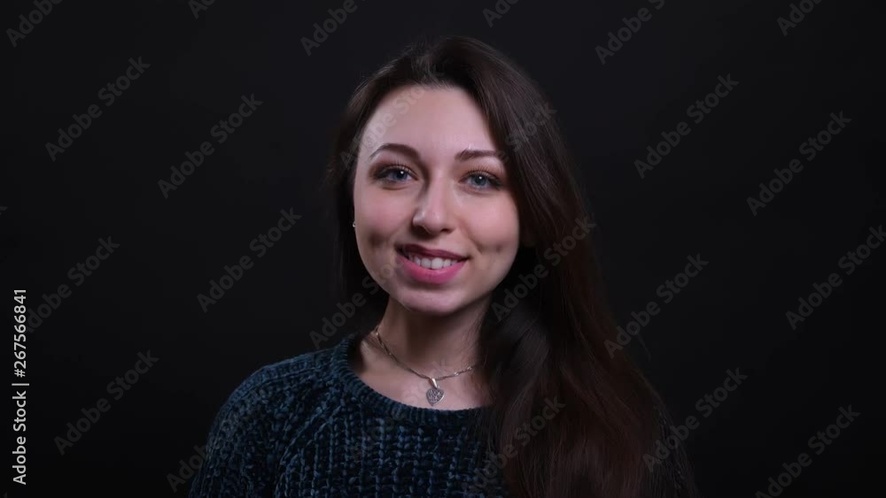 Closeup portrait of adult beautiful caucasian brunette female smiling happily looking at camera with background isolated on black Closeup portrait of adult beautiful caucasian brunette female smiling happily looking at camera with background isolated on black