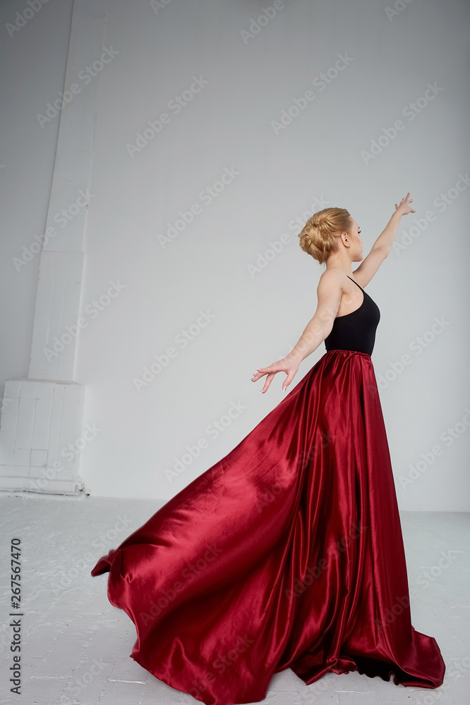 Fototapeta premium A gymnast in a dark top and a red silk skirt. The color of passion, of aggression. Tango. Plastic body, airiness , weightlessness and lightness.