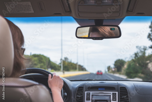 The girl is driving on the highway in Portugal. View from the back seat of the car on the windshield, road and the driver