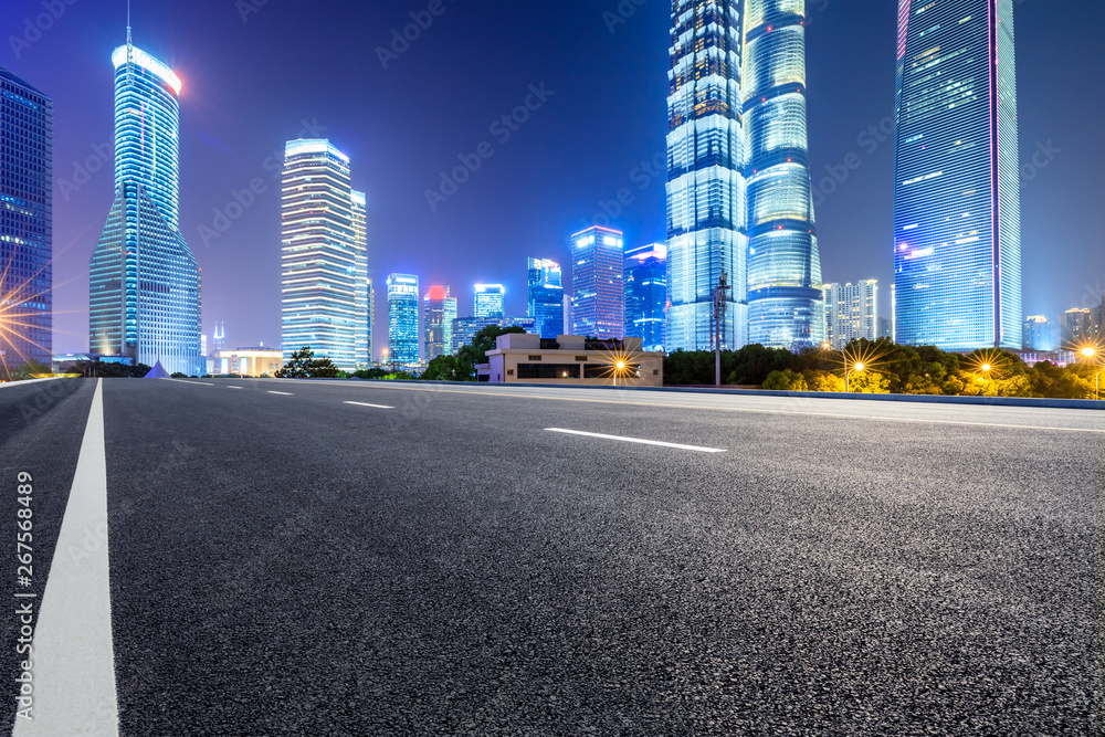 Naklejka premium Shanghai modern commercial office buildings and empty asphalt highway at night
