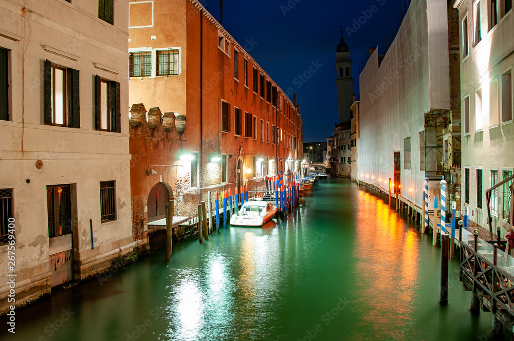 Night panorama view to Venice canals. Typical Venice street with canal, boat and famous architecture. Historical centre, canals at night.