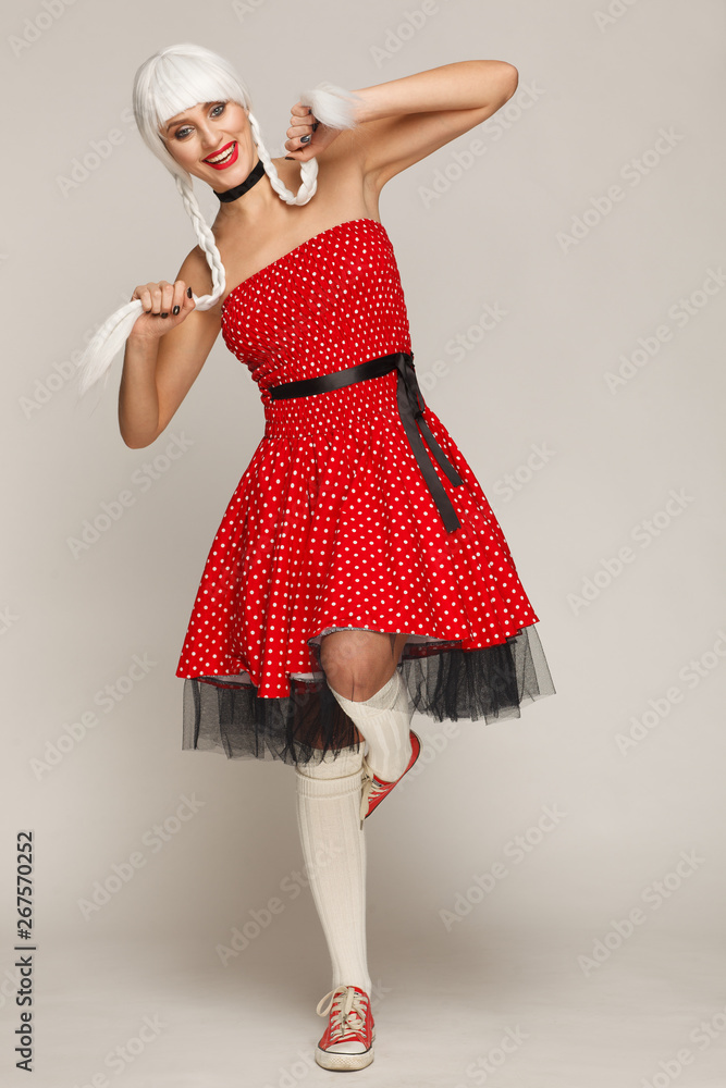 Φωτογραφία Portrait of a woman in a white wig, red dress and sneakers