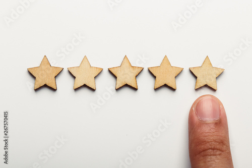 Hand pointing wooden five star shape on white background