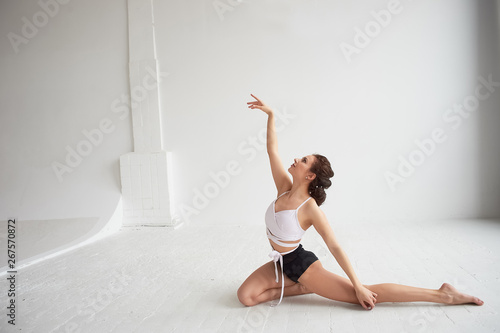 Gymnast dancing with a transparent film on a white wall and floor. Grace and healthy lifestyle.