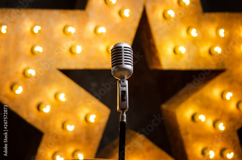 Microphone on theater or karaoke stage, golden luminous star on background