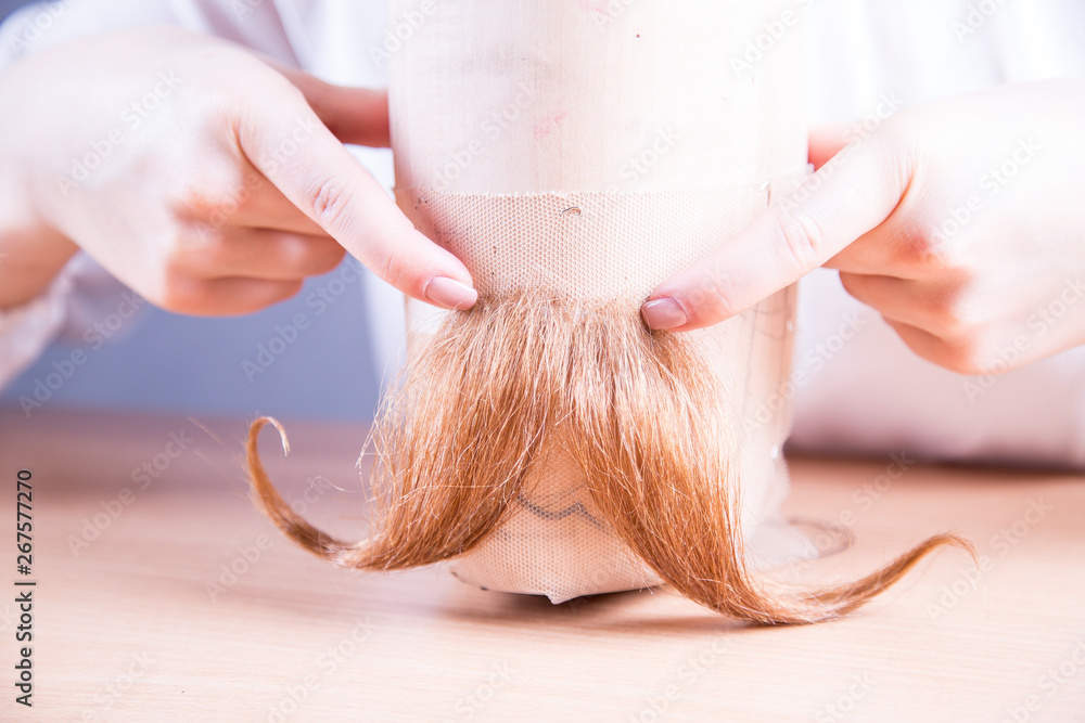 Fototapeta premium Dłonie młodej kobiety robiącej sztuczne wąsy. 