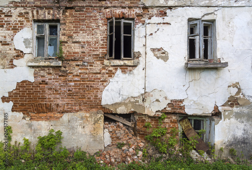 Fototapeta Naklejka Na Ścianę i Meble -  The wall of the old house with Windows, requiring repair. Fallen off plaster. Brick wall