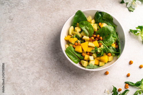 exotic salad with mango, nut, chickpeas, on a grey marble backdrop