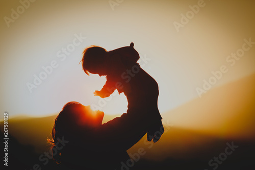 mother and little baby play at sunset nature