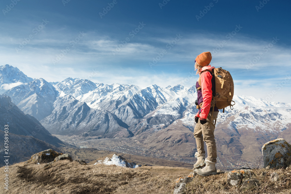 Fototapeta premium Portrait of photographer hipster tourist girl in sunglasses and a hat against the background of snow-covered Caucasus mountains. Photo travel concept