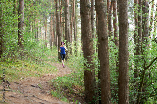 Athletic young woman in pink sneakers run in spring forest