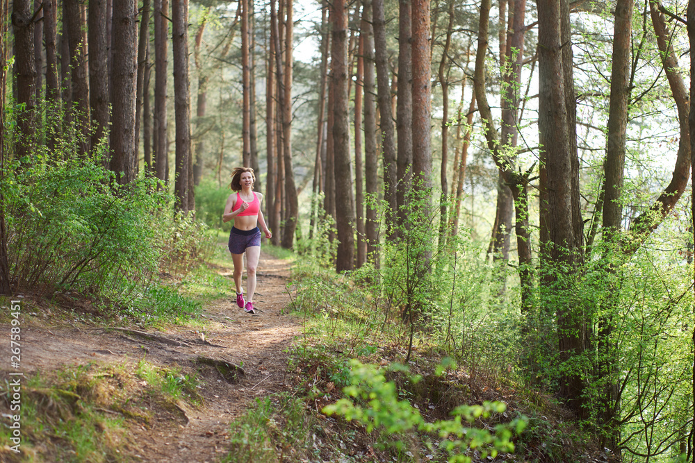 Athletic young woman in pink sneakers run in spring forest