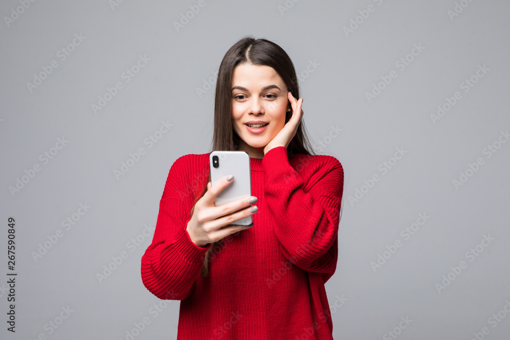 Closeup of young happy woman wearing in red sweater with mobile phone, over white background Closeup of young happy woman wearing in red sweater with mobile phone, over white background