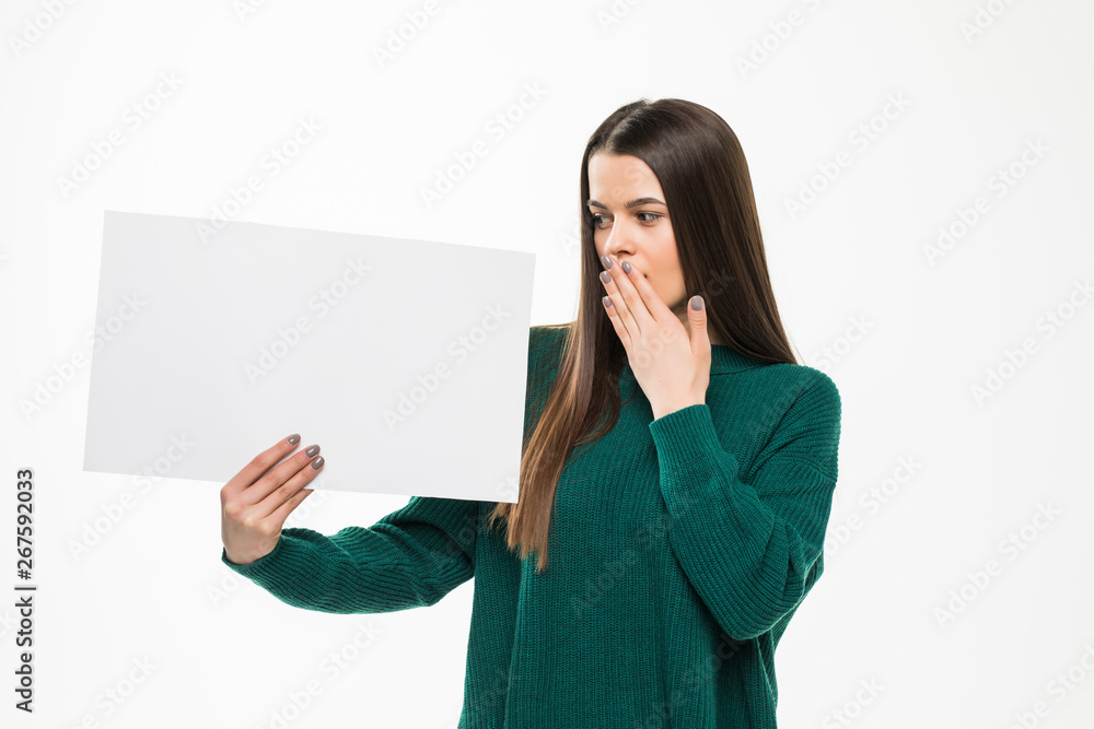 Young pretty woman holding white blank shocked wearing in green sweater isolated on white background Young pretty woman holding white blank shocked wearing in green sweater isolated on white background