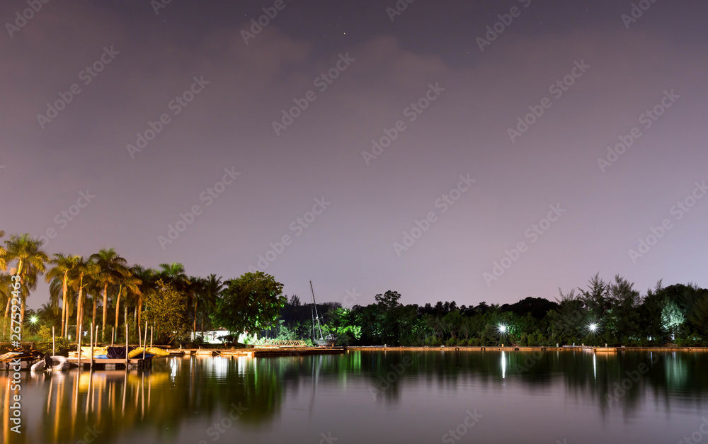 Horizontal view of lake and nature during dusk with night stars and smooth reflection on waters