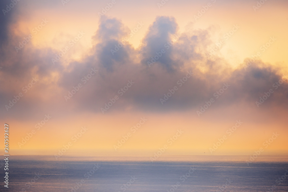 Minimalistic seascape. Misty clouds over the sea at sunrise.