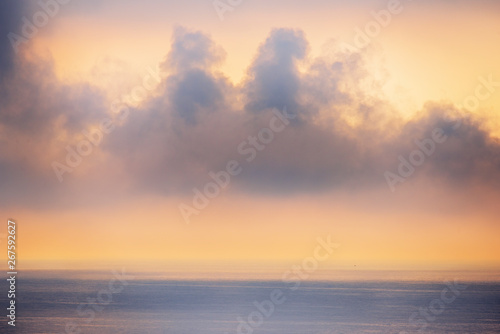 Minimalistic seascape. Misty clouds over the sea at sunrise.