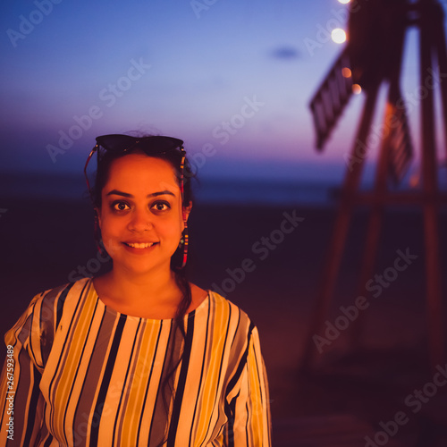 A girl with gleaming eyes and beautiful smile and warm light on her and blue background with lights and a windmill. photo