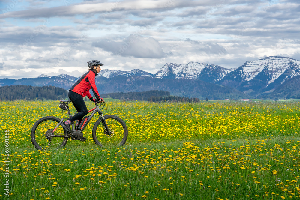 senior woman mountainbiking on a e-mountainbike in early spring, in the Allgaeu Area, a part of the bavarian alps,Germany senior woman mountainbiking on a e-mountainbike in early spring, in the Allgaeu Area, a part of the bavarian alps,Germany