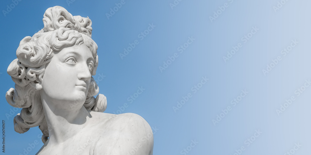 Ancient statue of sensual Italian renaissance era woman with long neck and curly hairs at blue sky gradient background, Potsdam, Germany