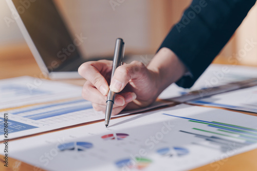 Businesswoman holding pen pointing on summary report chart and calculate finance in office.